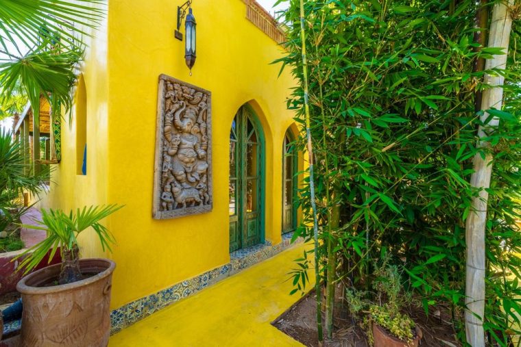 Saffron patio wall framed by bamboo and palms