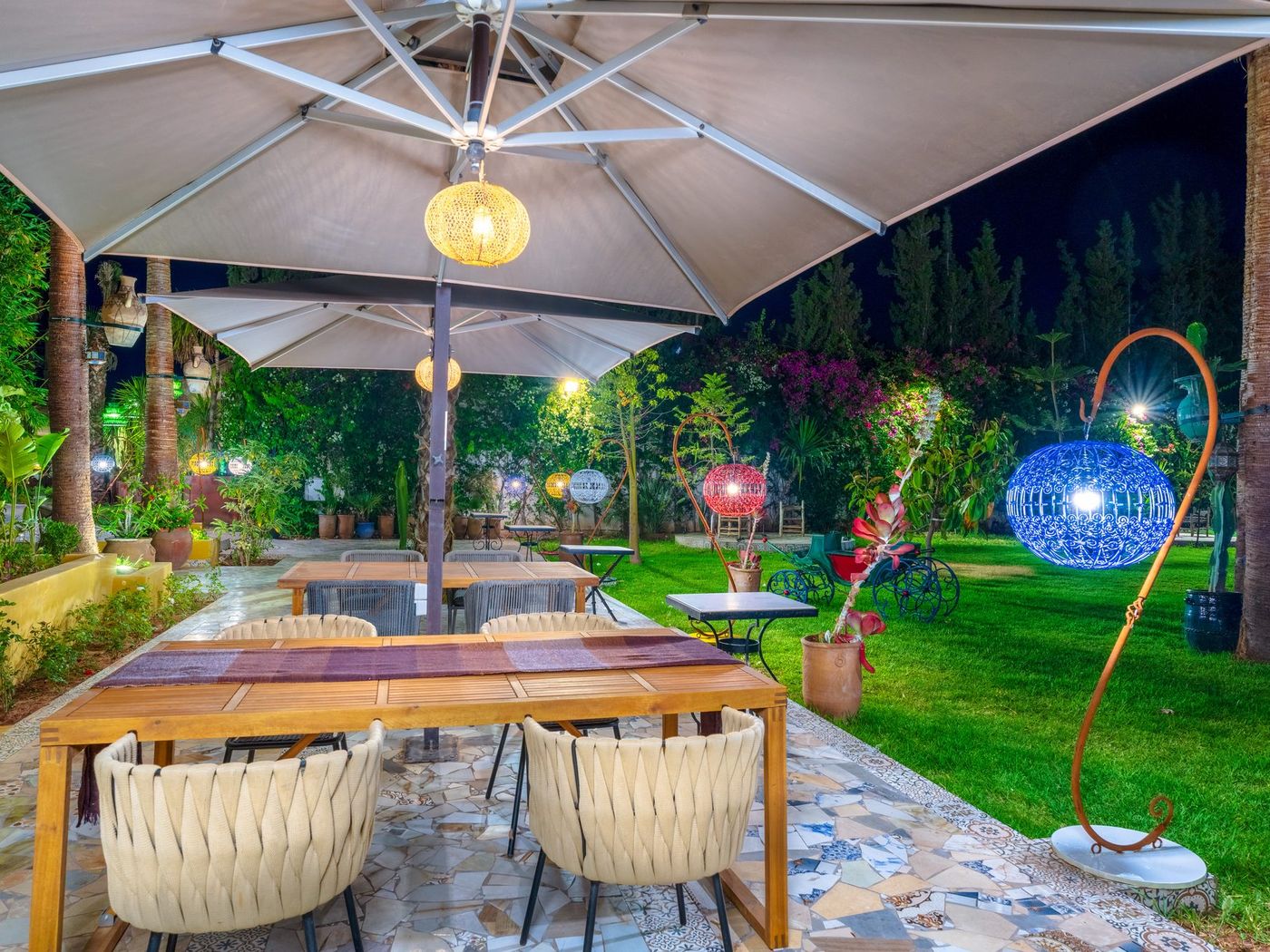 The estate gardens after dark, tables laid under warm light