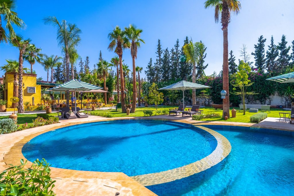 The round pool bordered by palms and loungers