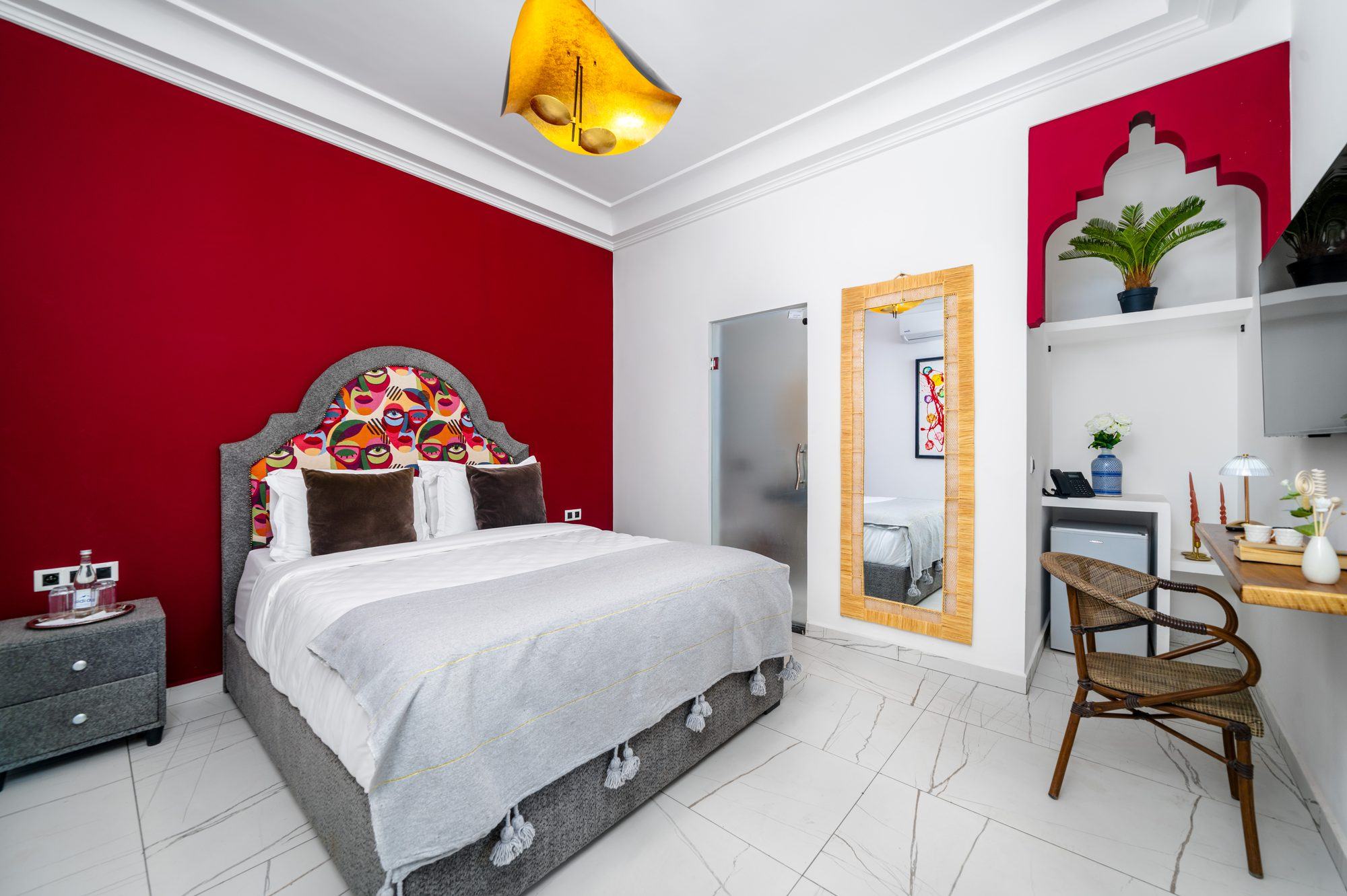 Standard room at Jnane Rihane with a crimson accent wall and a carved plaster niche