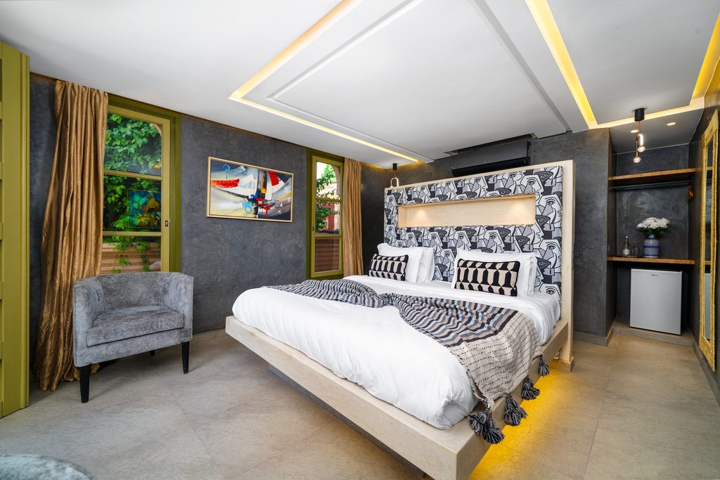 Standard room in soft grey with an armchair and garden doors