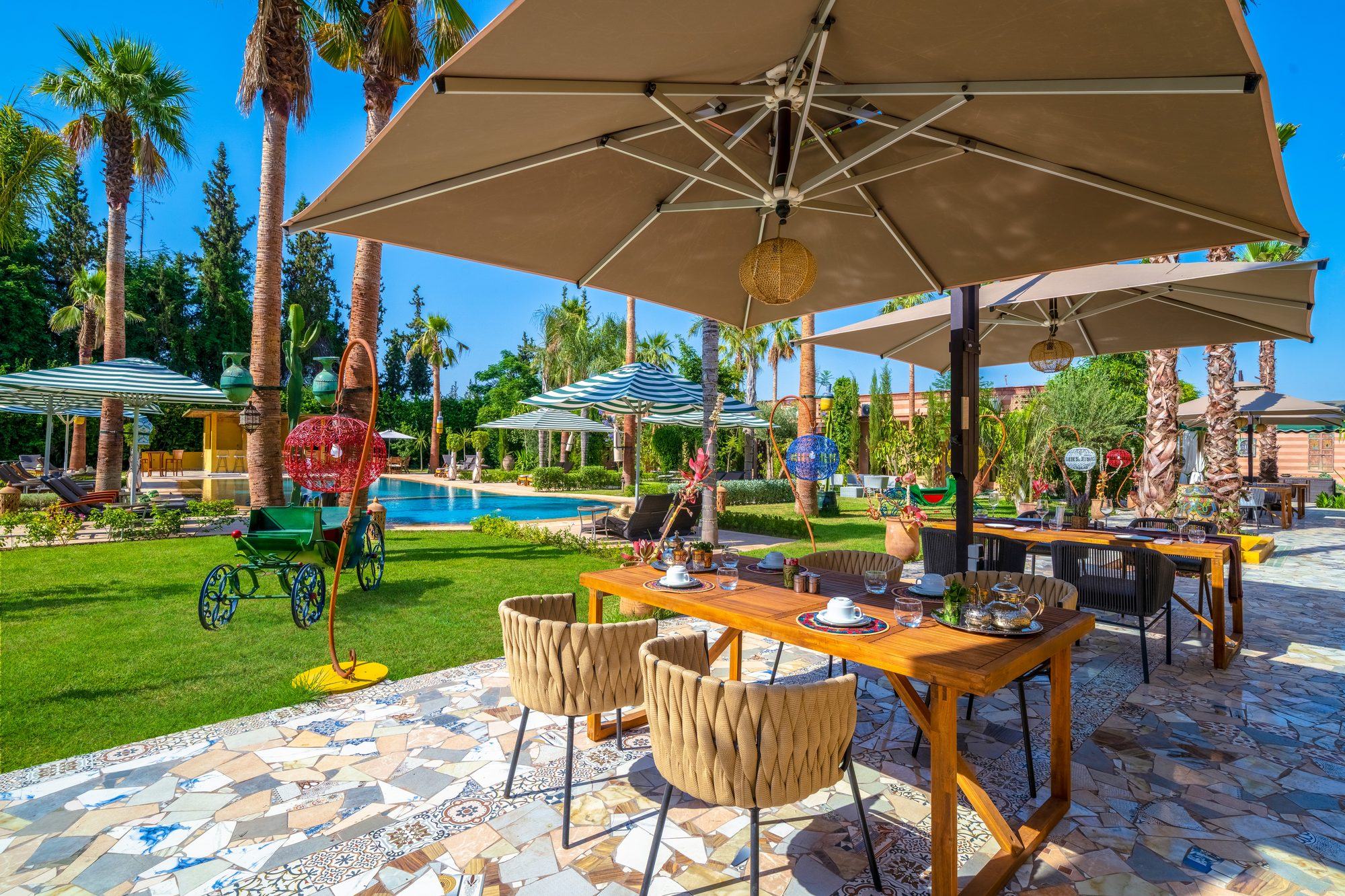 Table laid in the gardens of Jnane Rihane, parasols and palms