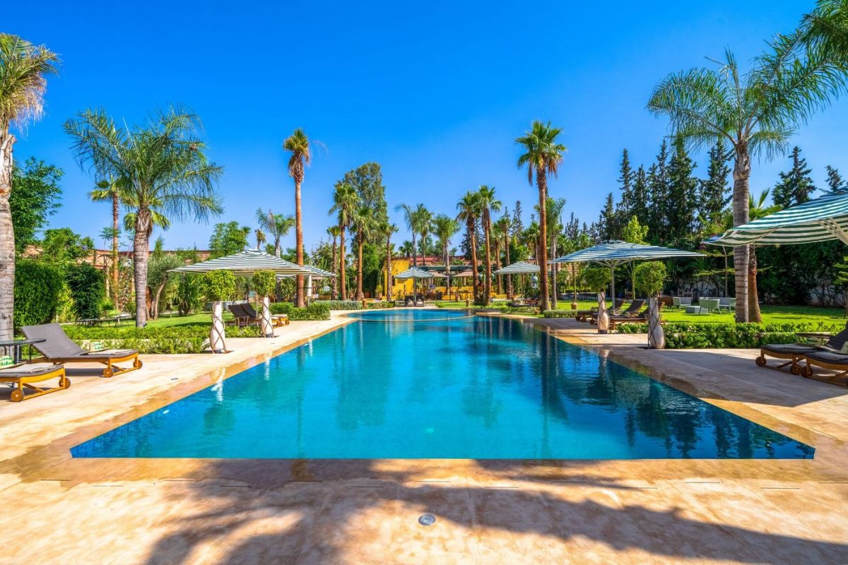 The main pool of the estate bordered by palms and green parasols