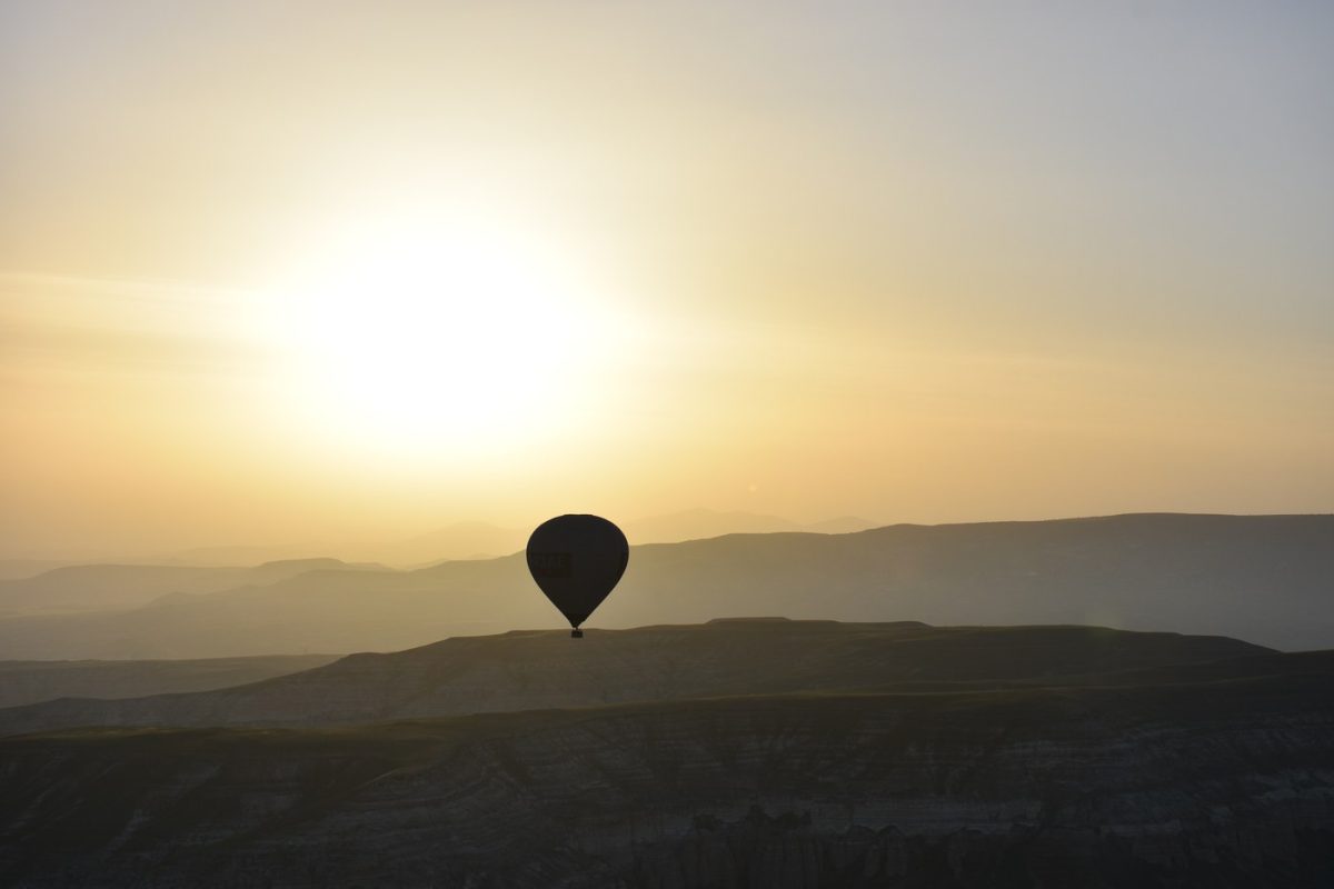Hot-air balloons floating over a valley at first light
